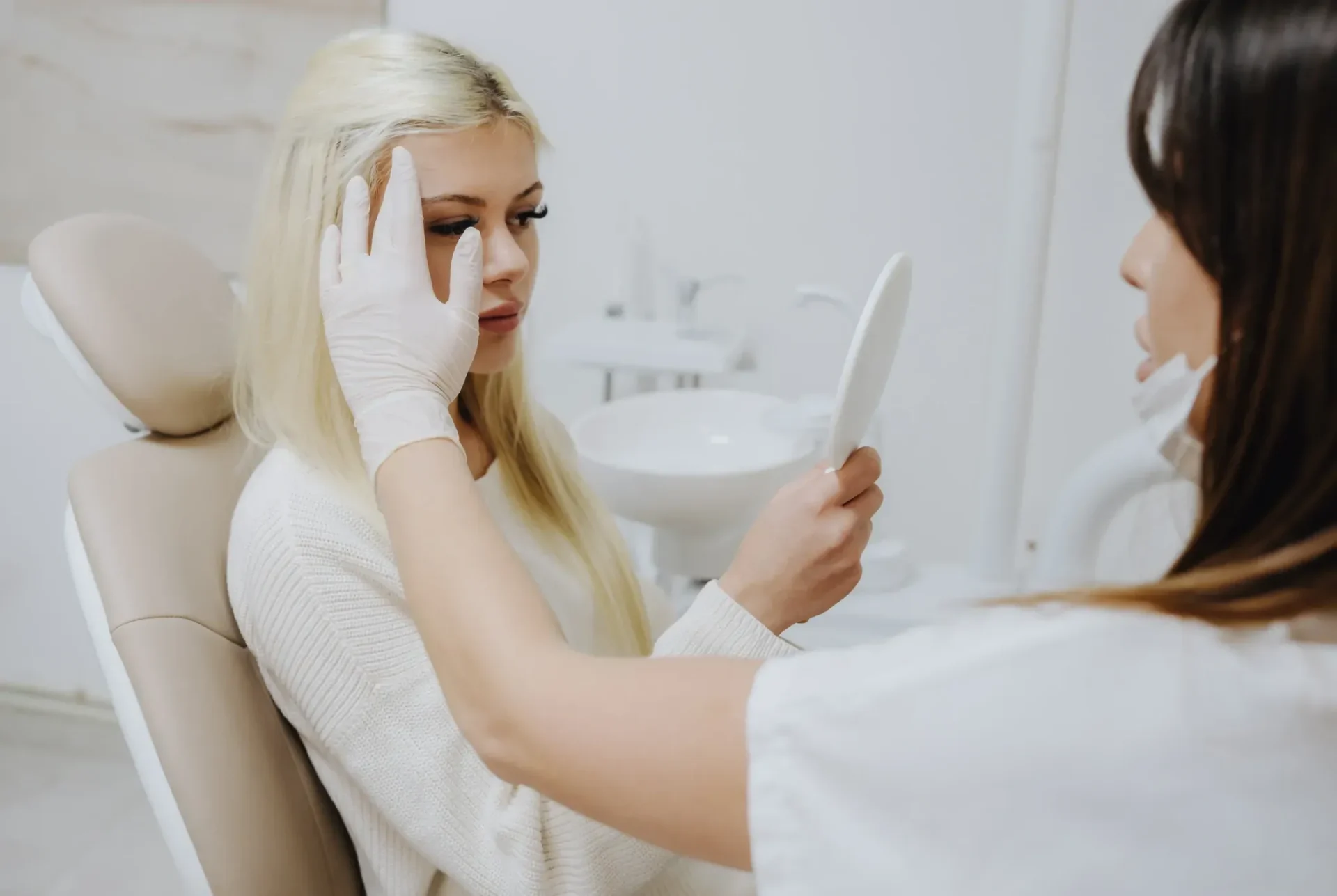 Woman holding mirror during consultation at clinic.